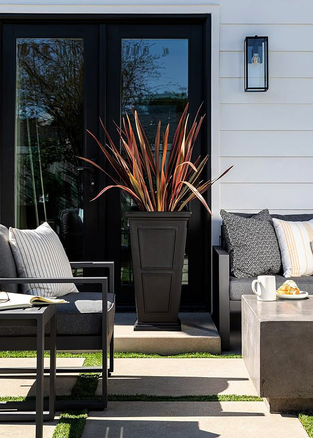 A patio with sleek black furniture and a vibrant potted plant, creating a stylish and inviting outdoor space.